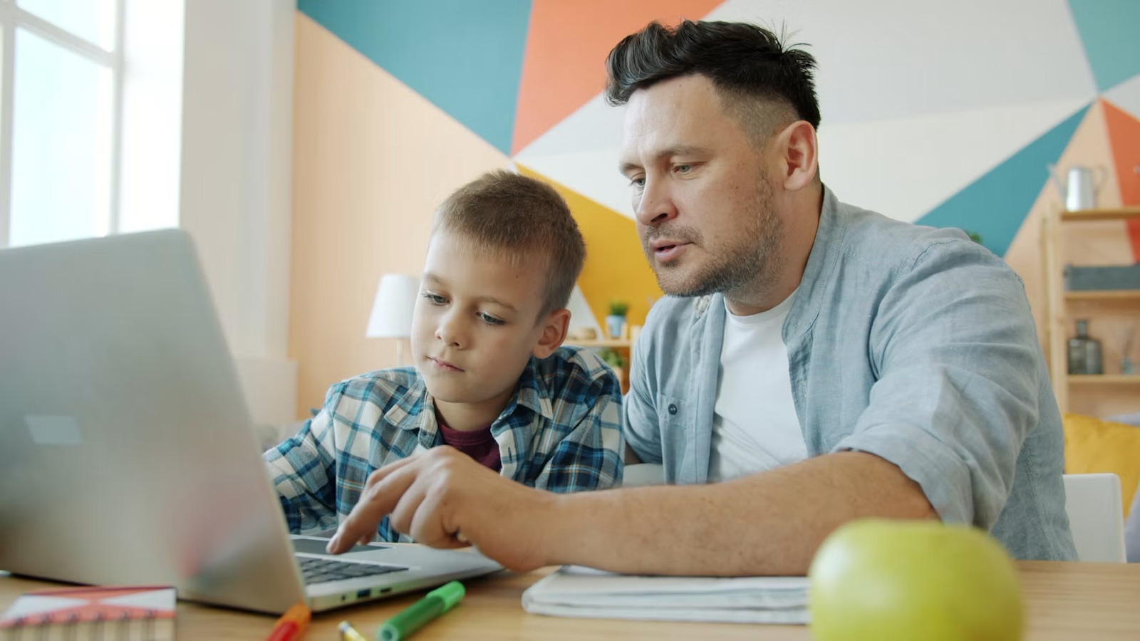A parent and child sitting together at a laptop at the start of the school year